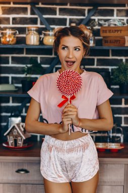 Mutfakta pembe elbise ile onun elinde büyük bir lolipop sarışın kadın