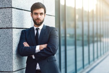 Duvara yaslanmış ofis binası arka plan üzerinde poz elbiseli genç işadamı portresi