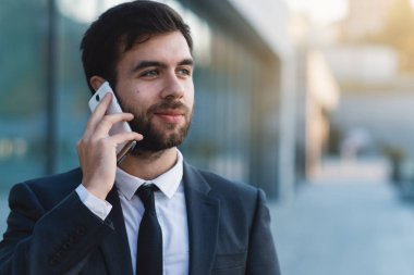 İşadamı Smartphone cep telefonu ile iş kurma açık havada karşı konuşuyor. Arka plan bulanık