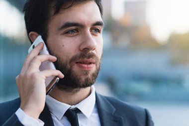 Yakın çekim işadamı Smartphone cep telefonu ile iş kurma açık havada karşı konuşuyor. Arka plan bulanık