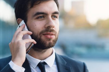 Yakın çekim işadamı Smartphone cep telefonu ile iş kurma açık havada karşı konuşuyor. Arka plan bulanık