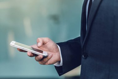 Elbiseli bir smartphone kullanarak bir iş adamı. Arama ve sosyal ağlar kavramı. Yakın çekim. Arka plan bulanık