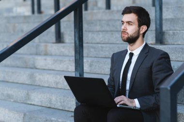 Belgili tanımlık merdiven üstünde a laptop ile kucağında oturan ve düşünceli arıyorum açık havada işadamı