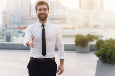 Genç yakışıklı işadamı beyaz gömlekli adam ve kravat şehrin arka planı yardım için bir tebrik eder güneşli bir sevinçle gülüyor. Açık havada, arka plan bulanık.