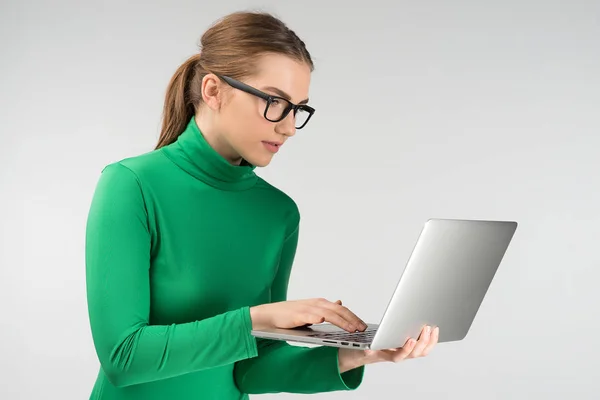 Woman  in profile works on a tablet while standing. Looking carefully at the screen