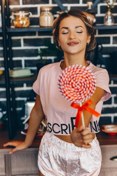 Pembe el ileri lolipop üzerinde mutfakta sarışın kadın