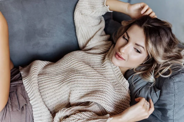 Modern bir sarışın kız kanepede yatan bir kazaklı closeup. Yan arıyorum