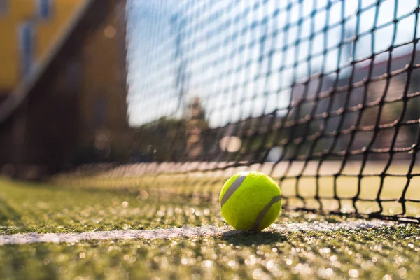 Primer plano pelota de tenis acostado en la línea blanca en la pista dura al lado de la red — Foto de Stock