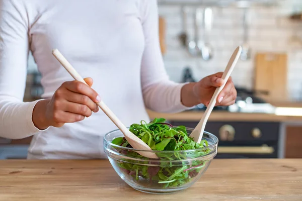 Primeros planos de las manos femeninas durante la cocción de un alimento saludable, revuelve con cucharas una ensalada — Foto de Stock
