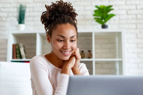 Mulher bonito olhando para a tela do laptop sentado no escritório e gentilmente sorrindo. - Imagem — Fotografia de Stock