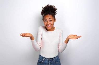 Mulatto kız omuz silkiyor ve kameraya bakarak gülümseyerek