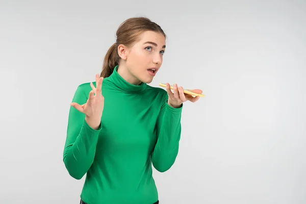 Surprised  young woman talking on a cell phone holding it in her — Stock Photo, Image