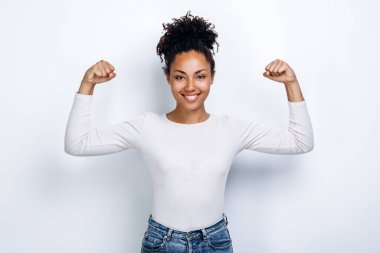 Kollarını ve pazılarını kameraya gösterirken gülümseyen genç ve güzel kadının portresi.