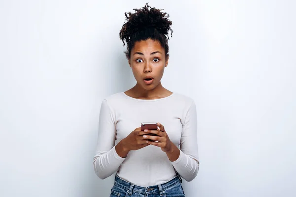 stock image Surprised girl with a phone in the hands of the studio with a white background