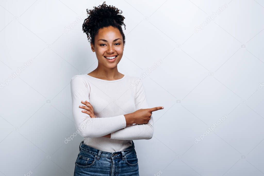 Young, beautiful girl with curly hair shows a finger on a copy space