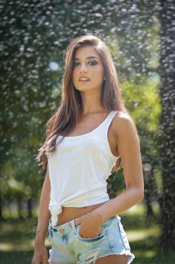 Sprey su beyaz T gömlek ile seksi kadın portresi. O iyi bir nazik cilt, şehvetli duruş ve o gülümsüyor vardır. Mutlu genç kadın parkta. Gençlik bir yaşam tarzı. Mutluluk, neşe, yaz konsepti.
