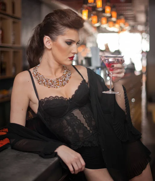 Sensual girl with long legs and high heels sitting on the chair in bar  drinking .Handsome girl wearing beautiful body and high heels in indoor scene.Fashion model with long sexy legs drink cocktail.