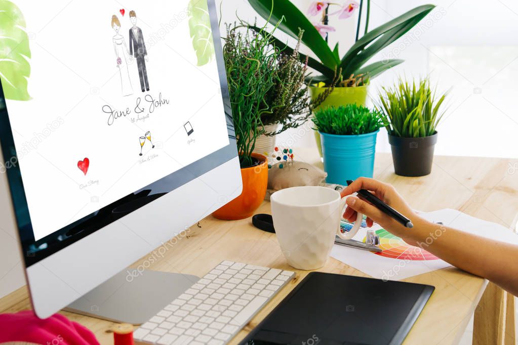 Graphic designer using pen tablet to design a wedding website. All screen graphics are made up.