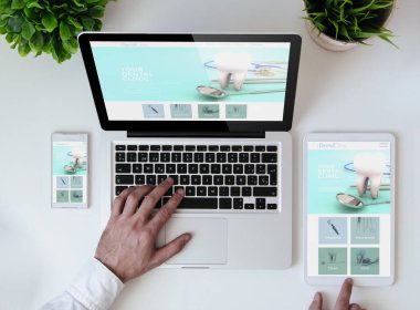 ofis masa tablet, smartphone ve serin duyarlı tasarım diş kliniği Web sitesi gösterilen laptop ile erkek el