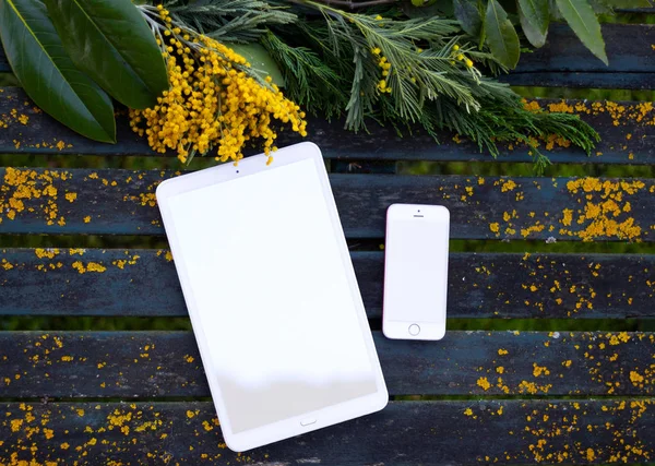 Vintage table with mobile, tablet and yellow wildflowers