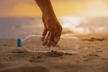 El tutmak Temizleme günbatımı olay yerinde plajda plastik şişe
