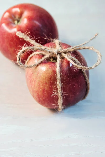 Apples tied with a rope on a light wooden background