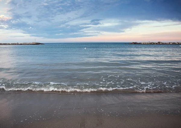 Sea, sky, coast and sand, background with a copy space. Beautiful seascape. Panoramic dramatic sunset sky and Ligurian sea.