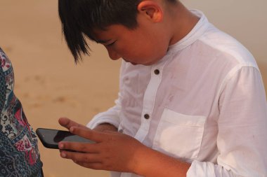 Genç çocuk kumsalda oynuyor.