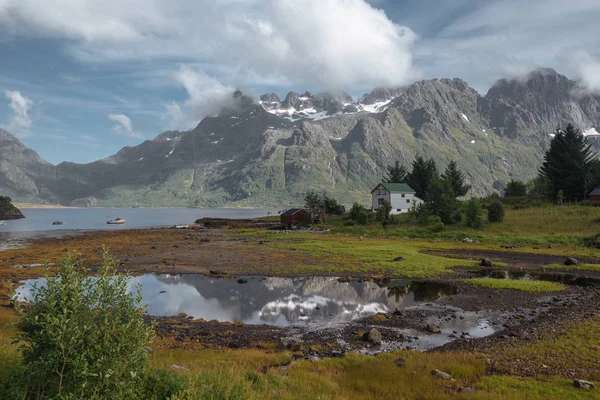 Casa bianca e specchio lago con vista sulle montagne innevate e sul mare in Norvegia in estate — Foto Stock