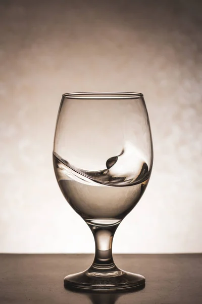 Concept shot of a glass with water waves and splashes on white background