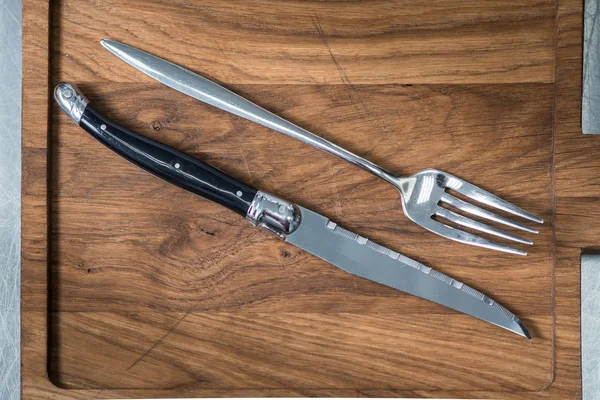 Cuchillo de cocina y un tenedor se colocan en una tabla de cortar —  Fotos de Stock