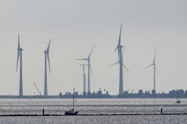 Hollanda 'daki Grevelingen Gölü 'nde, ön planda küçük bir yat ile büyük rüzgar türbinlerinin, biri inşasına göre uzun mesafe görünümü