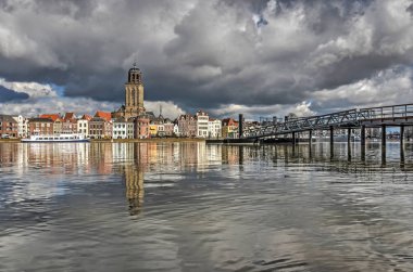 The city of Deventer, The Netherlands and its new ferry pier reflecting in the calm waters of the river IJssel clipart