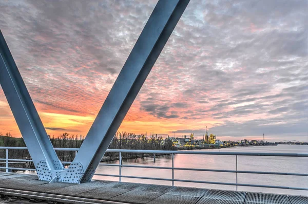 Chemours 製油所は 燃えるような夕日に向かって Beneden Merwede 川を渡る鉄道橋から Sliedrecht ネザーランド 2015 ビュー — ストック写真