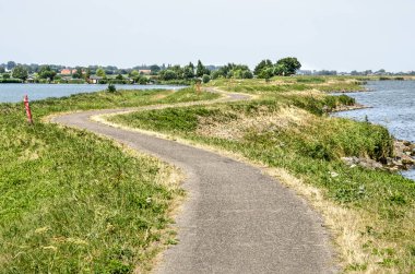 Dolambaçlı bir dike Gölü IJsselmeer Gölü Kinselmeer Amsterdam yakınındaki Waterland bölgedeki arasındaki yolda bisiklet