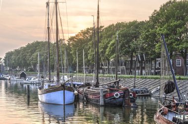 Hoorn, Hollanda, 9 Mayıs 2018: Gökyüzü altında Grashaven Marina'da tarihi mavnalar batan güneşin kırmızı renkli