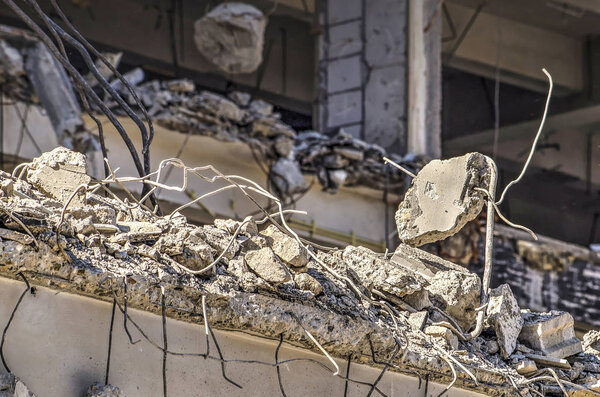 Close up of a building in the process of being demolished, with reinforcement bars sticking out of broken concrte floors
