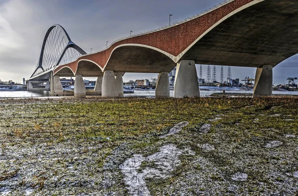 低植生とナイメーヘン オランダに近いワール川の氾濫原で雪の薄層付近のコンクリート レンガと都市の鋼鉄アーチ橋 クロッシング Oversteek — ストック写真