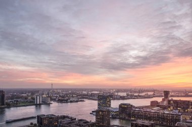 Rotterdam, Hollanda, 12 Kasım 2018: muhteşem bir gökyüzü günbatımı Nieuwe Maas nehri üzerinde ve limanlar ve her iki tarafta mahalleler