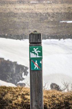 Hiçbir izinsiz girme simgesi hem de uyarı işareti İzlanda'daki bir uçurumun kenarındaki ahşap direk