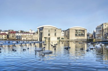 Reykjavik, Izlanda, 27 Şubat 2019: Belediye Binası, bitişik banliyö mahalle ve göl Tjornin altında dramatik bir gökyüzü altında şafak