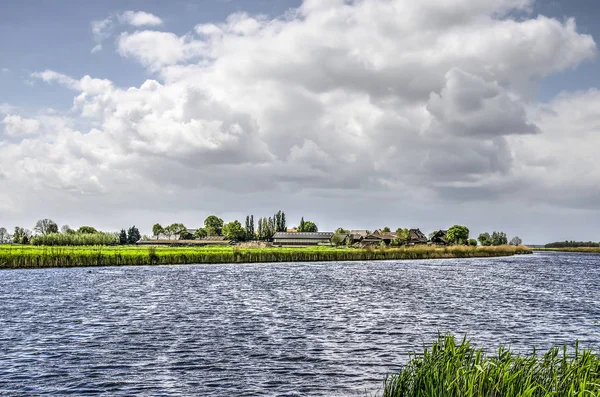 De Donk hamlet built on a low river dune  at the banks of a canal in the Alblasserwaard polder in the Netherlands under a cloudy sky in springtime