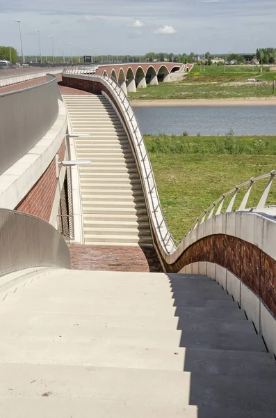 Nijmegen, Hollanda, 25 Nisan 2019: Beton merdivenler Köprü De Oversteek'ten sel yataklarına ve yeni nehir kanalına iner