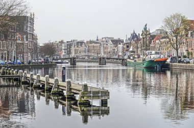 Haarlem, Hollanda, 2 Nisan 2019: Tarihi evler, ahşap bir iskele, bir köprü ve tarihi bir iç mavna ile nehir Spaarne görünümü