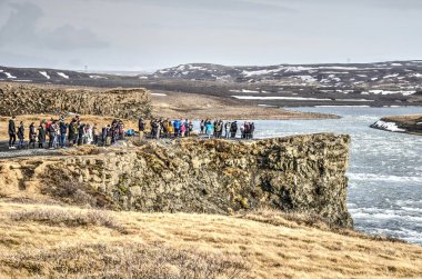 Gulfoss, İzlanda, 27 Şubat 2019: turistlerin blöf ün üstünde durup vadideki nehir, akıntı ve şelaleye bakan manzara