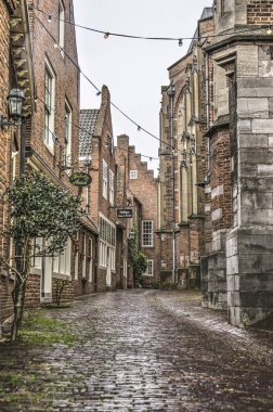 Nijmegen, Hollanda, 25 Nisan 2019: yağmurlu bir günde eski evler ve Aziz Stephen kilisesi arasındaki dar sokak