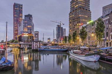 Rotterdam, Hollanda, 21 Mayıs 2019: Eski ve yeni binalar ve tarihi mavnaların karışımıyla alacakaranlıkta Wijnhaven limanı