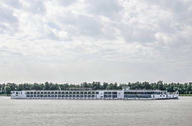 Gorinchem, Hollanda, 10 Haziran 2019: Canlı bulut oluşumları ile bir yaz gökyüzü altında Merwede nehri üzerinde geçen nehir kruvazörü