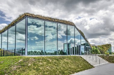 Werkendam, Hollanda, 3 Temmuz 2019: Biesbosch Milli Parkı'ndaki müze restoranının ön cephesine yansıyan muhteşem bulutlarla gökyüzü