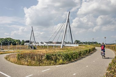 Zwolle, Hollanda, 5 Ağustos 2019: Westenholter köprüsüne yaklaşan bisikletçi, banliyö mahallesine doğru yoğun bir trafik kavşağından geçiyor